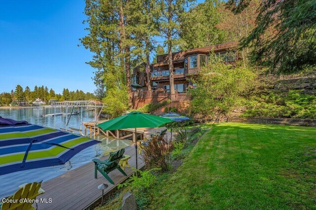 exterior space featuring a lawn, a water view, and a boat dock