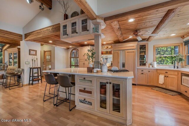 kitchen featuring light wood-style floors, a sink, beam ceiling, and light countertops