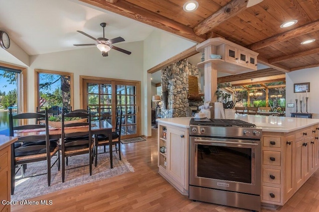 kitchen featuring light countertops, a ceiling fan, gas stove, and light wood-style floors