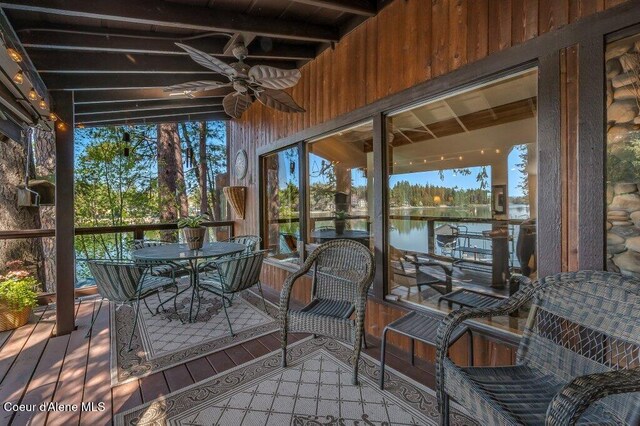 wooden deck with a ceiling fan, outdoor dining space, and a water view