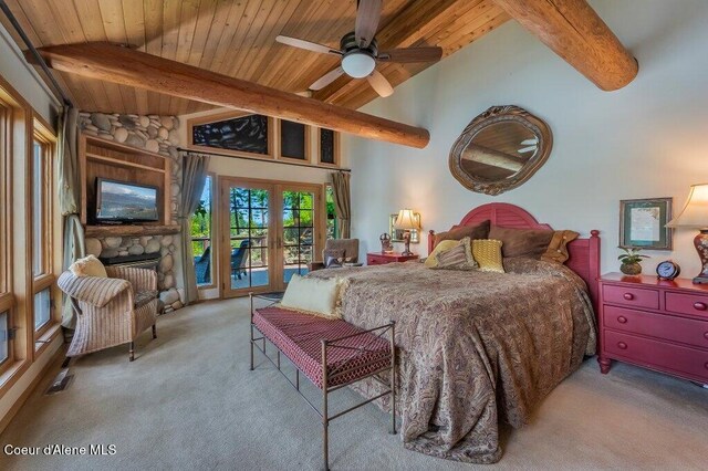carpeted bedroom with wooden ceiling, lofted ceiling with beams, a stone fireplace, and access to exterior
