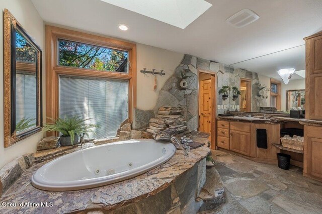 bathroom with a tub with jets, a healthy amount of sunlight, a skylight, and visible vents