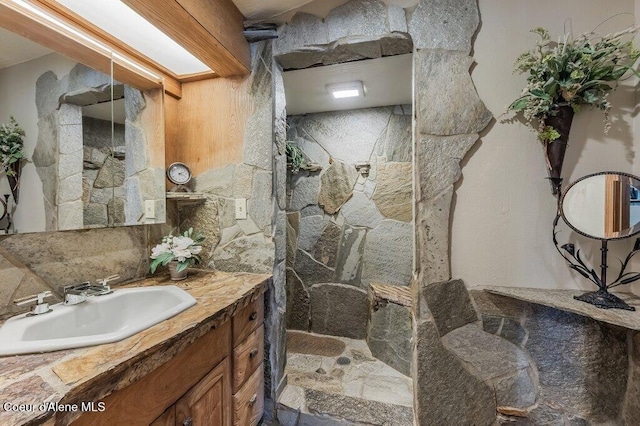 bathroom with vanity, a shower, and stone finish floor