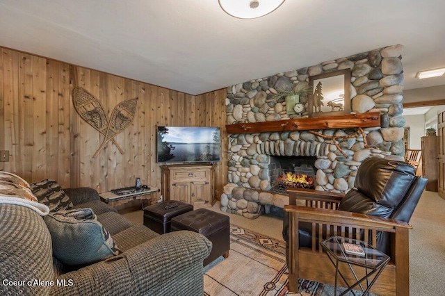 living room featuring wooden walls, a stone fireplace, and light carpet
