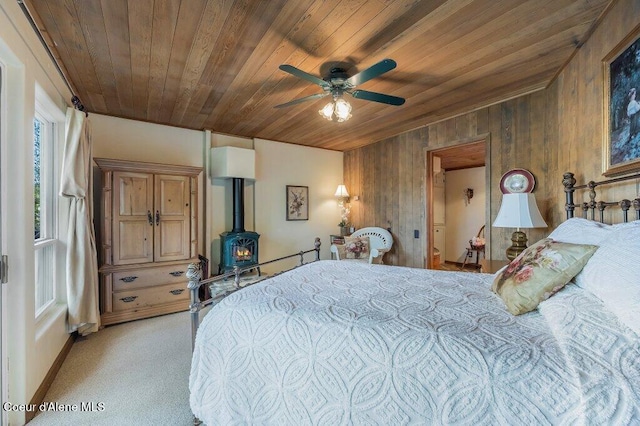 bedroom featuring wooden walls, light colored carpet, wood ceiling, and a wood stove