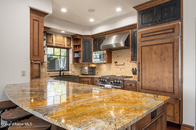 6012 W Quartzite Ln, Coeur Dalene, ID 83814 - kitchen with appliances with stainless steel finishes, wall chimney range hood, a sink, a peninsula, and decorative backsplash