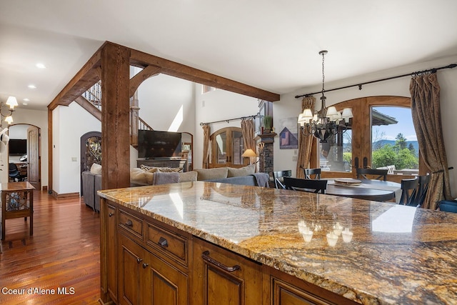 6012 W Quartzite Ln, Coeur Dalene, ID 83814 - kitchen with a chandelier, arched walkways, dark wood-style floors, brown cabinets, and hanging light fixtures