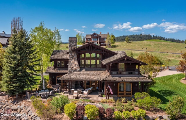 6012 W Quartzite Ln, Coeur Dalene, ID 83814 - back of property featuring a balcony, a patio area, a chimney, and an outdoor hangout area