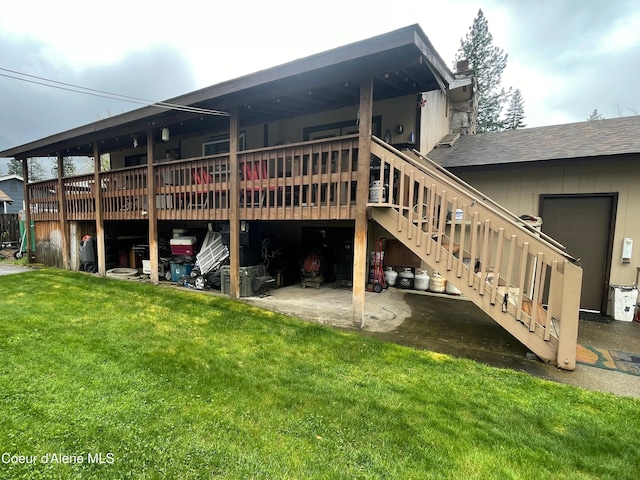 back of house featuring a shingled roof, a deck, stairway, a chimney, and a lawn