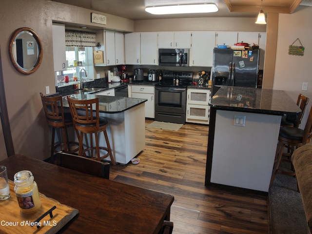 kitchen featuring a peninsula, white cabinets, a sink, dark wood finished floors, and black appliances