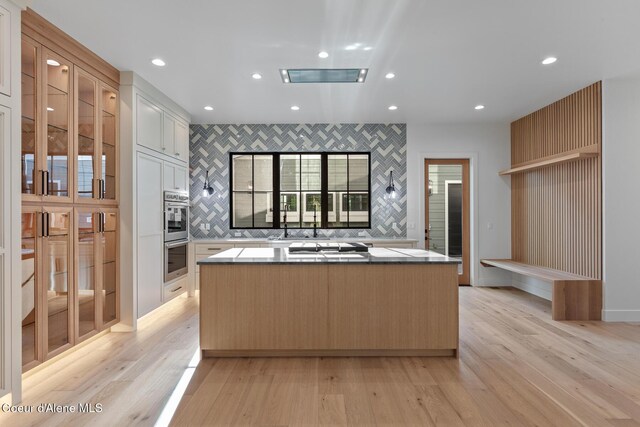 kitchen featuring appliances with stainless steel finishes, a center island, recessed lighting, light wood-type flooring, and backsplash