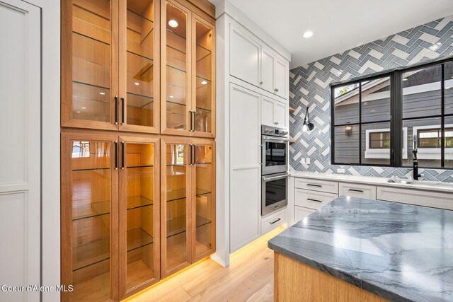 907 N B St, Coeur Dalene, ID 83814 - kitchen featuring double oven, glass insert cabinets, white cabinets, a sink, and light wood finished floors