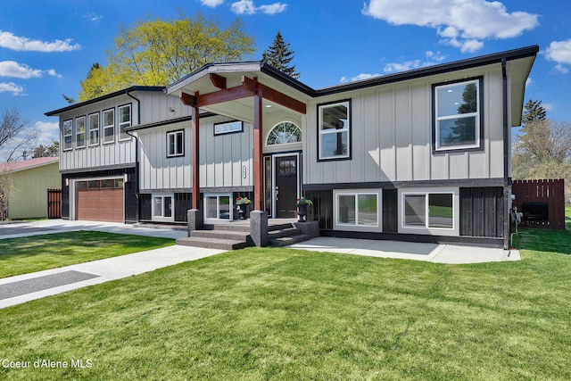 bi-level home featuring fence, an attached garage, a front lawn, board and batten siding, and concrete driveway