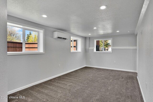 empty room featuring recessed lighting, a textured ceiling, a wall mounted AC, and dark carpet
