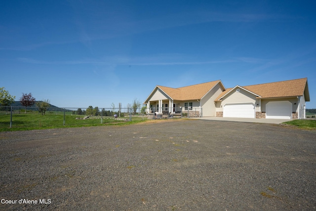 view of front of home with fence, stone siding, aphalt driveway, and a garage