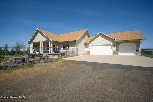 view of front of property featuring driveway, roof with shingles, a garage, fence, and stone siding