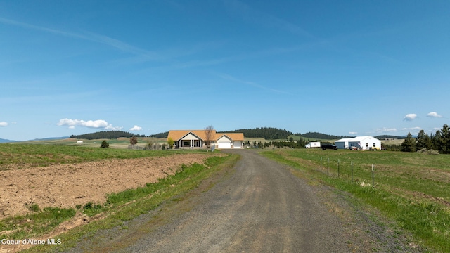 view of road with a rural view and dirt driveway