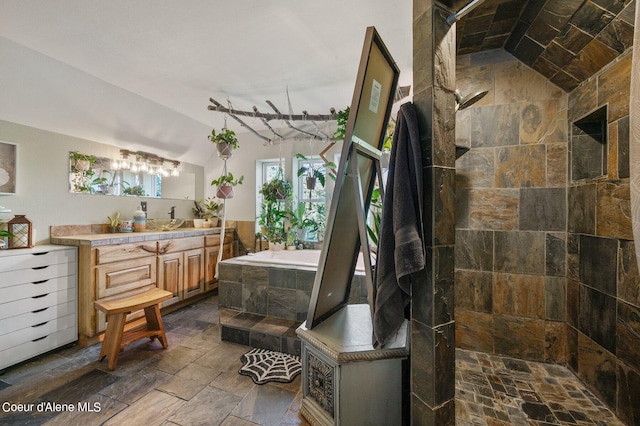 bathroom featuring stone tile floors, lofted ceiling, a bath, and a tile shower