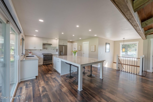 10792 N Magic Ct, Hayden, ID 83835 - kitchen featuring stainless steel appliances, a sink, under cabinet range hood, white cabinets, and a kitchen island