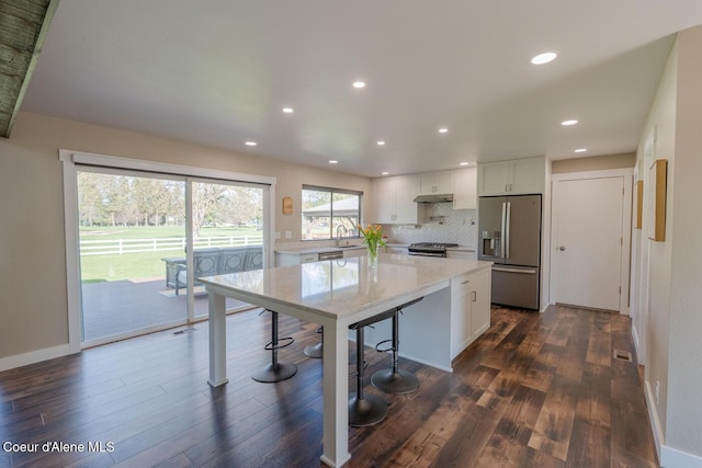 10792 N Magic Ct, Hayden, ID 83835 - kitchen with stainless steel appliances, a kitchen island, dark wood-style flooring, white cabinetry, and backsplash