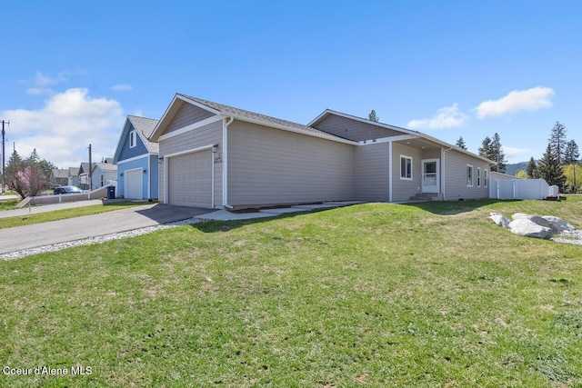 view of front of property featuring a front yard, driveway, fence, and a garage