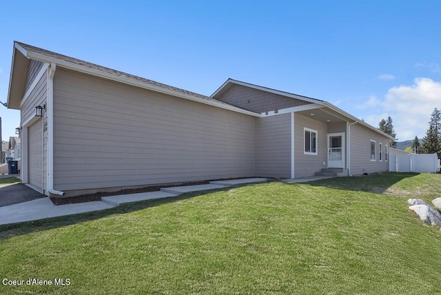 view of side of home with a lawn, fence, and entry steps
