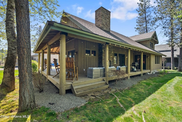 504 Hornby Pl, Dover, ID 83825 - back of house with board and batten siding, a chimney, roof with shingles, a lawn, and covered porch