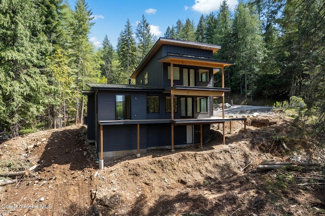 rear view of house featuring a view of trees