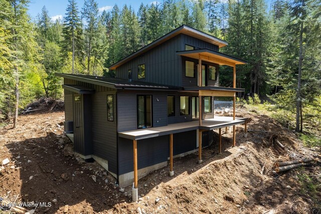 back of house featuring a deck and a wooded view