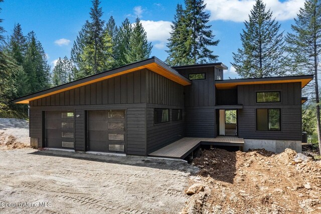 contemporary home featuring dirt driveway, board and batten siding, and cooling unit