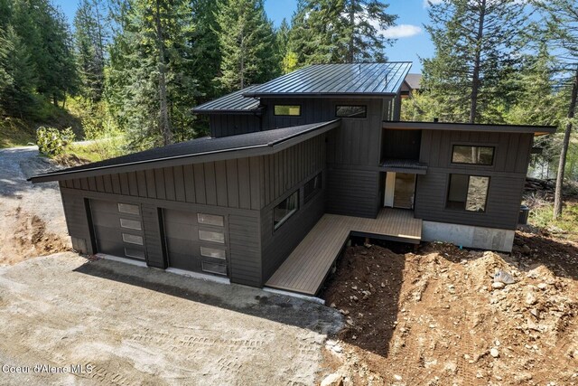 view of front of house with a garage, board and batten siding, a standing seam roof, driveway, and metal roof