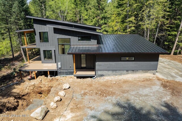 contemporary house featuring board and batten siding, a forest view, and metal roof