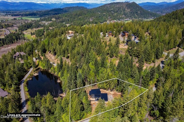 aerial view with a water and mountain view and a wooded view
