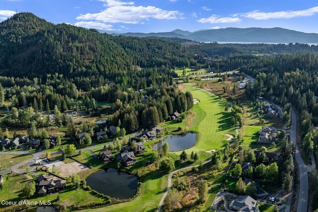 birds eye view of property featuring golf course view, a water and mountain view, and a wooded view
