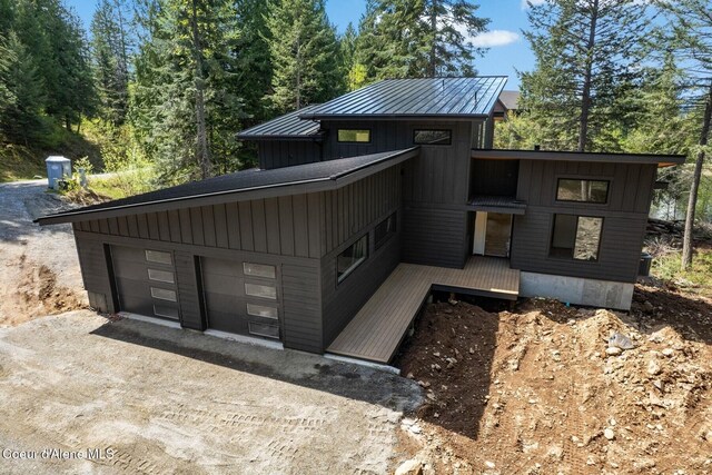 view of front of property with board and batten siding, a standing seam roof, metal roof, driveway, and a garage