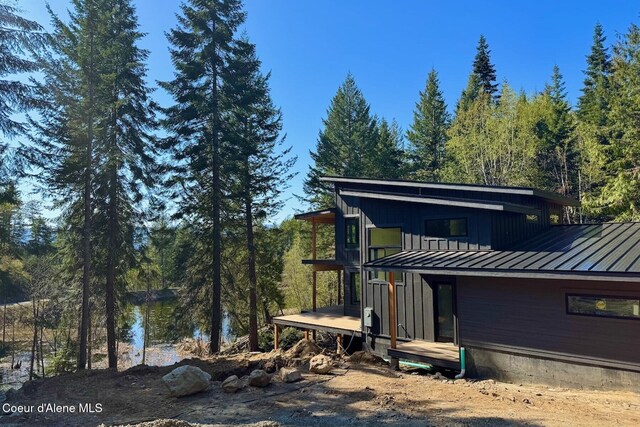 view of home's exterior with a wooded view, metal roof, a deck, and a standing seam roof