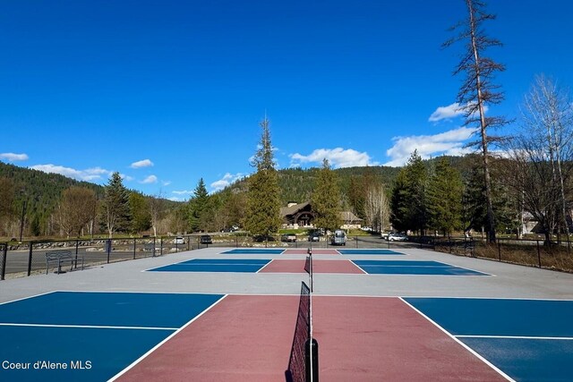 view of sport court with fence, community basketball court, and a wooded view