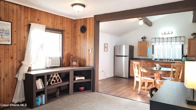 carpeted dining room featuring wooden walls, lofted ceiling with beams, a sink, and cooling unit