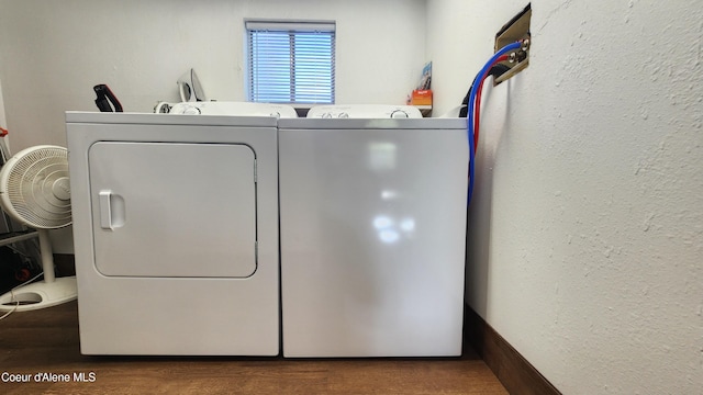 clothes washing area with a textured wall, laundry area, washing machine and dryer, and wood finished floors