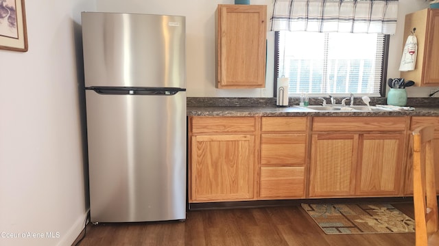 kitchen with freestanding refrigerator, dark countertops, a sink, and dark wood-type flooring