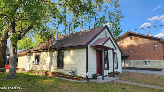 view of side of property with a lawn, cooling unit, and metal roof