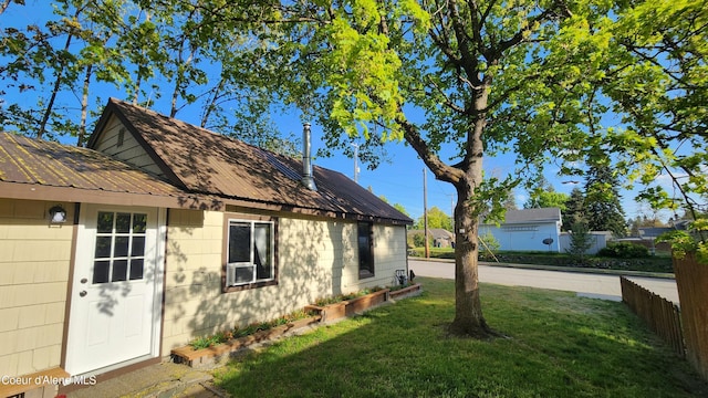 view of side of property featuring a yard, fence, and metal roof
