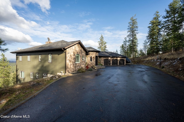 5969 W Highland Dr, Coeur Dalene, ID 83814 - view of property exterior featuring stone siding, driveway, and a chimney