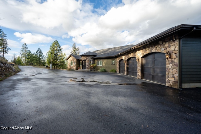 5969 W Highland Dr, Coeur Dalene, ID 83814 - view of front facade featuring a garage, stone siding, and aphalt driveway