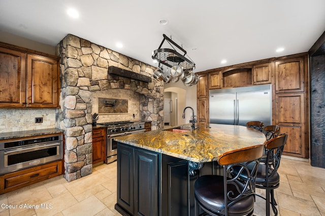 5969 W Highland Dr, Coeur Dalene, ID 83814 - kitchen with high end appliances, arched walkways, a sink, stone tile flooring, and dark stone counters