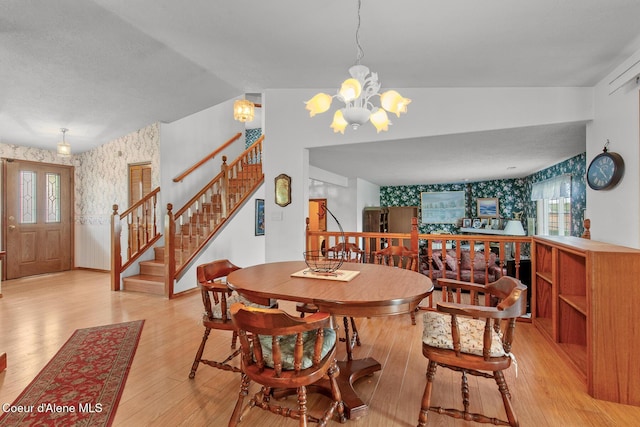 404 W 18th Ave, Post Falls, ID 83854 - dining area featuring stairway, a chandelier, vaulted ceiling, wallpapered walls, and light wood-style floors