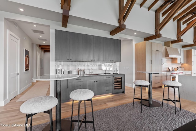 6869 S Gozzer Rd Unit C201, Harrison, ID 83833 - kitchen featuring beverage cooler, custom range hood, decorative backsplash, light wood finished floors, and beamed ceiling