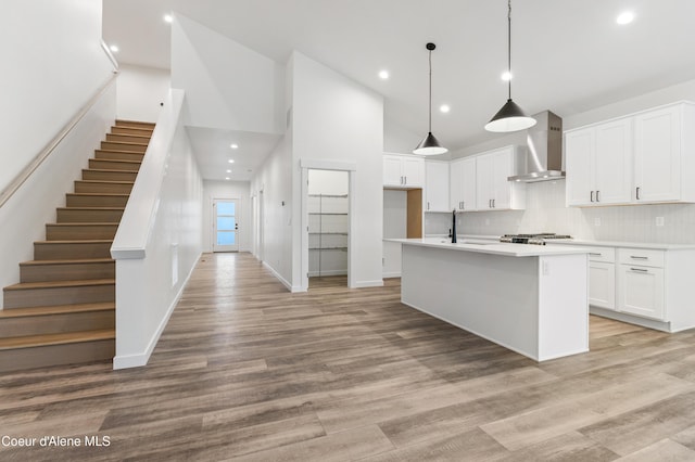 6696 Portrush Dr, Rathdrum, ID 83858 - kitchen featuring wall chimney range hood, a sink, light countertops, high vaulted ceiling, and backsplash