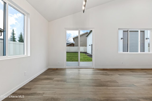 6696 Portrush Dr, Rathdrum, ID 83858 - empty room featuring baseboards, vaulted ceiling, wood finished floors, and a wealth of natural light