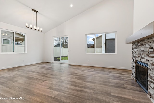 6696 Portrush Dr, Rathdrum, ID 83858 - unfurnished living room featuring high vaulted ceiling, an inviting chandelier, a stone fireplace, and wood finished floors